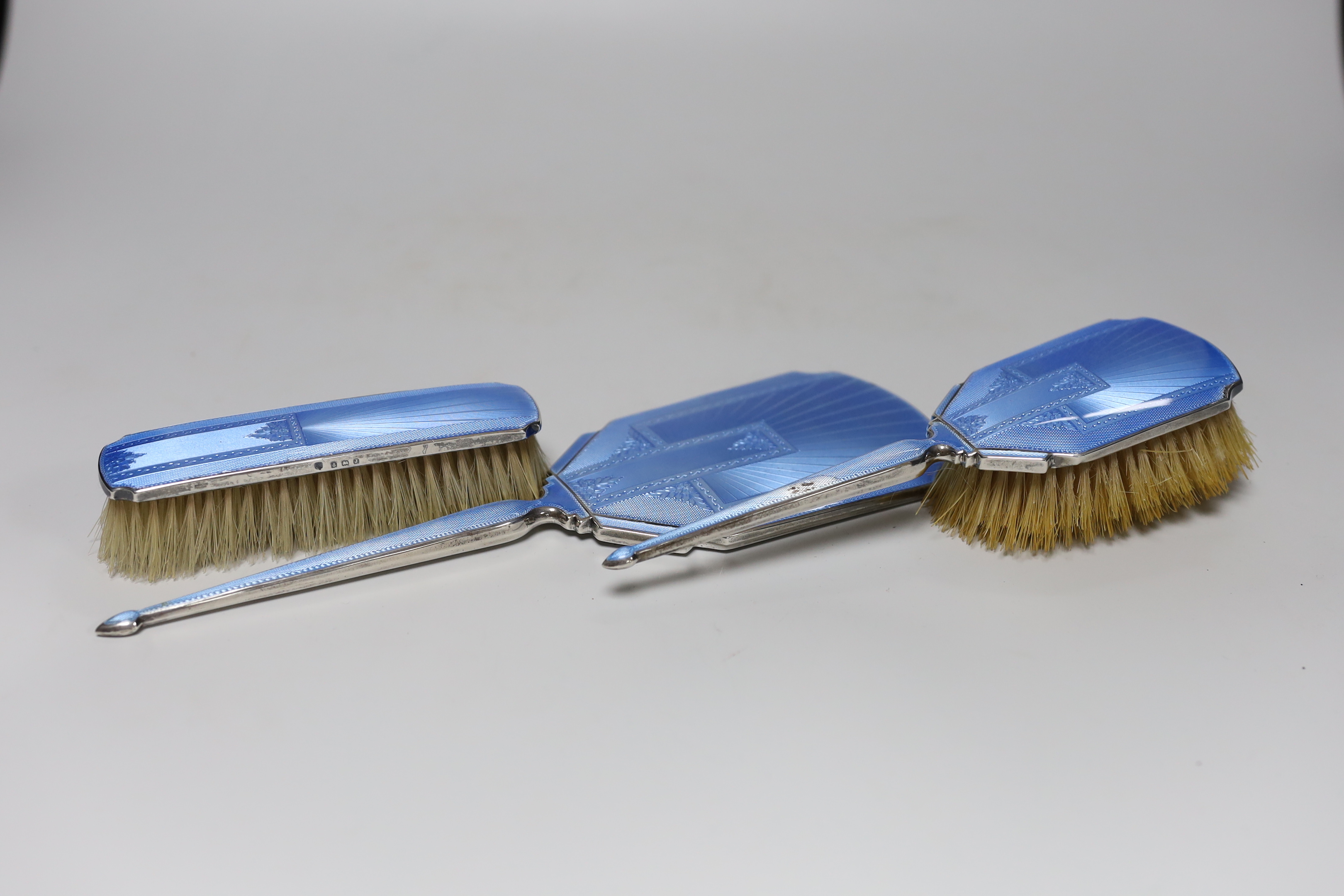 A George V Art Deco silver and blue guilloche enamel mounted three piece mirror and brush set, C.S. Green & Co, Birmingham, 1933, mirror 29.6cm.